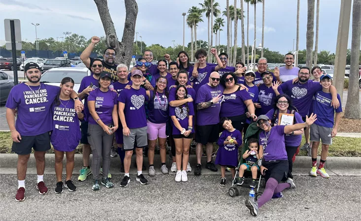 Thirty people posing for a group shot wearing PanCAN PurpleStride T-shirts.